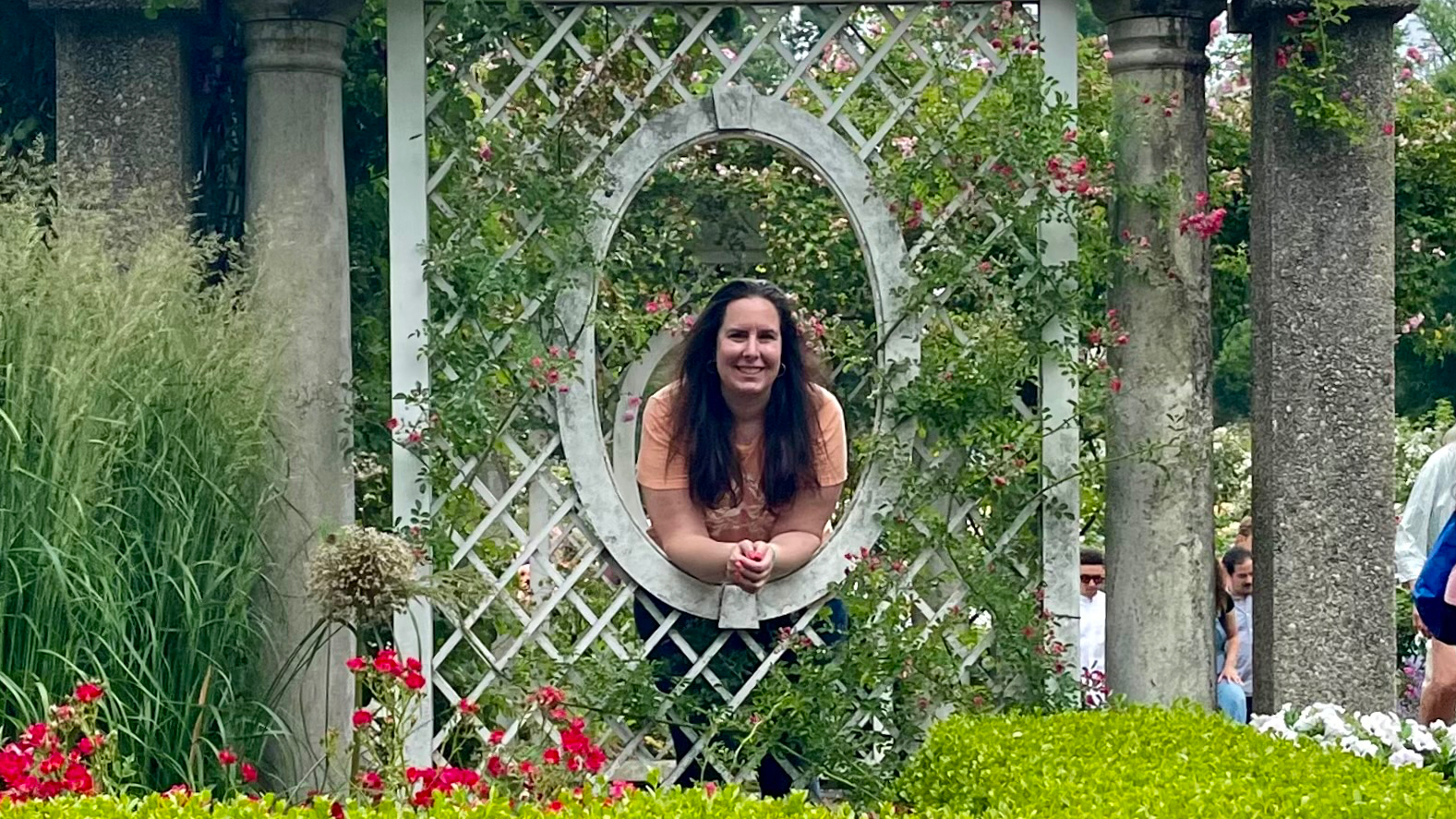 Blaire looking through a lattice in a garden